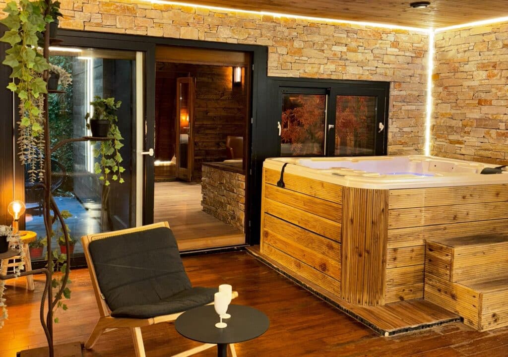 Spa privatif en bois du cottage suédois avec mur en pierre et fauteuils